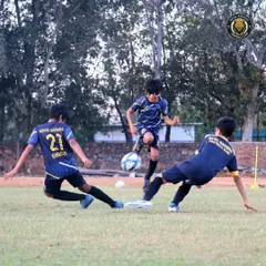 A dynamic moment in a training scrimmage as one player skillfully evades two sliding tackles. Our practice games are designed to be competitive and fun, simulating real match pressure.