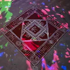 The finished Mandana seen under colorful disco lights, adding a modern, festive twist to the traditional artwork. The white lines of the design stand out sharply against the earthy red base.