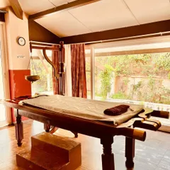 This is a traditional Ayurvedic massage table, known as a 'Droni'. Made from medicinal wood, its design is integral to treatments like Abhyanga and Shirodhara, ensuring the therapeutic oils are effectively used and collected.