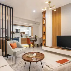 This living room is connected to an open-plan kitchen and dining area, separated by a stylish slatted partition. This design maintains a sense of openness while creating distinct zones for different activities.