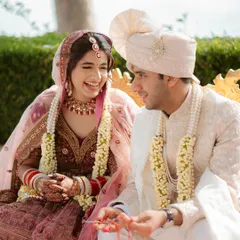 A candid shot of the bride and groom laughing together during a wedding ritual, capturing their genuine connection.