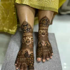 An elegant foot mehandi design with beautiful peacock figures on the feet and ankles, combined with traditional jhumka and floral patterns.