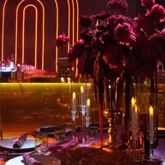 A moody and romantic tablescape from the theatre-themed Sangeet. The deep red florals, personalized napkins, and glowing candles set against a neon-lit bar created a dramatic and intimate dining experience.