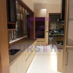 This view of the Bharatpur project showcases the galley-style layout, with the island on one side and the main counter on the other. We incorporated decorative fluted glass shutters on the upper cabinets, adding a touch of traditional elegance to the modern design.