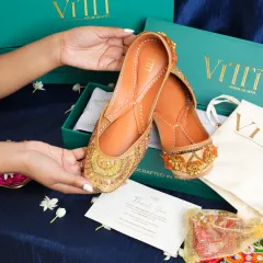 A pair of intricately embroidered juttis being unboxed. We focus on the unboxing experience to create a sense of excitement and luxury for fashion products.