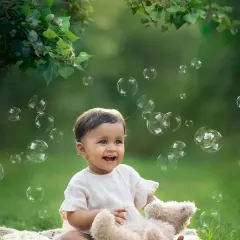 The pure joy of a baby surrounded by bubbles in a beautiful park setting. This is a perfect shot for a one-year-old baby photoshoot.