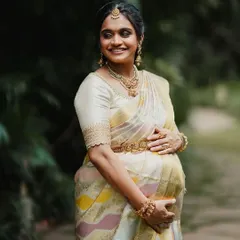 A beautiful maternity portrait. The client cradles her baby bump, wearing the elegant off-white saree and custom blouse with scalloped sleeve details.