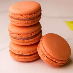 A stack of lovely orange-coloured macarons. These delicate French cookies are a perfect, light treat for any time of day.