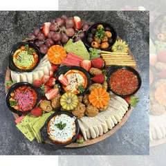Our Mezze Platter is a journey through Mediterranean flavors. This beautiful arrangement includes a variety of dips like hummus and muhammara, falafel, pita bread, fresh fruits, and olives.