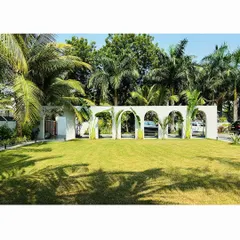 A wide view of the "Tropical Manor" lawn, where the arched wall acts as a sculptural backdrop to a sprawling green oasis, separating the garden from the driveway.
