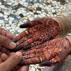 A beautiful moment between the couple, highlighting the deep, dark color of the bride's mehendi stain. This is the result of pure, natural henna and proper aftercare.