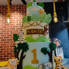 A full view of the impressive three-tier jungle safari cake, complete with a little explorer topper. This cake is perfect for a wild first birthday adventure.