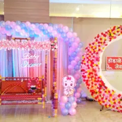 For this 'Dohale Jevan' baby shower, I combined modern and traditional elements. The setup features a large pastel balloon arch over a decorated swing (jhula) and a floral crescent moon photo point for guests.