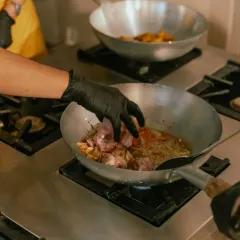 Knocking up a fresh batch of stir fry in a traditional wok over a high flame.