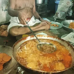 A glimpse into our kitchen during a busy catering event. Here, our cook is preparing a large quantity of a traditional fried delicacy, following the same methods we have used for decades to maintain authentic taste.