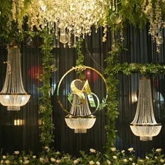 A close-up of the reception decor, showing hanging crystal chandeliers and a custom gold monogram of the couple's initials, framed by fresh greenery. These personalized details make the event unique.