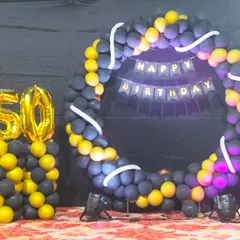 A different style for a 50th birthday, this setup uses a full balloon ring in black and yellow with large foil numbers on a separate pillar.