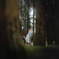 An embrace in the heart of the woods, where the deep shadows and tall trees create a moody, romantic atmosphere. This style of portraiture is for couples who love dramatic and evocative imagery.