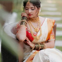 A classic, elegant bridal portrait. The bride's serene expression and the intricate details of her temple jewelry and saree are the focus of this beautiful shot.