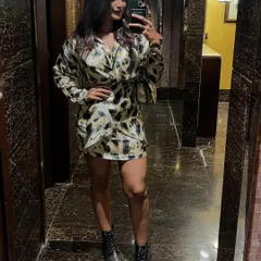 A mirror selfie showing off this fun animal print wrap dress. Paired with black combat boots, it creates a look that's both trendy and edgy.