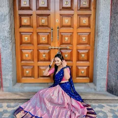 A happy client seated in a beautiful pink and royal blue silk Langa Voni. The rich texture of the silk skirt shines, making it perfect for photos.