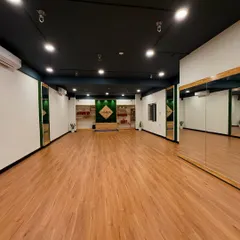 A wide-angle view of our practice hall, showcasing the expansive wooden flooring and mirrors that help create a focused environment for group classes.