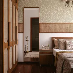 This guest bedroom is all about quiet comfort. We used mellow floral wallpaper, cane accents on the headboard and wardrobe, and touches of brass to create a warm, familiar, and welcoming space.