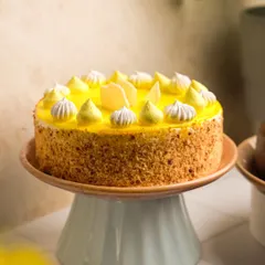A full view of a stunning mango cake on a pastel blue stand. This shot highlights the beautiful piping work and crumb coating, presenting it as a perfect centerpiece for any celebration.