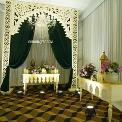 An elegant photo corner with a white carved arch, a crystal chandelier, and beautiful floral arrangements, perfect for capturing regal portraits.