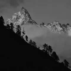 The same mountain peak, presented in black and white. This version emphasizes the sharp, jagged texture of the rock and snow, creating a timeless and dramatic mountain portrait.