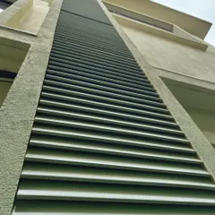 A close-up view of our sleek metal louvers installed on a residential building. This low-angle shot highlights the clean lines and precision of the installation, which provide both privacy and architectural style.