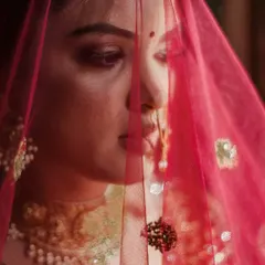 A close up, artistic shot of a bride through her pink veil. This photo captures a moment of quiet contemplation and highlights the delicate details of her look.