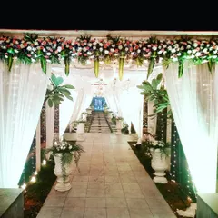 This is another perspective of the illuminated entrance pathway at night. The combination of soft fabrics, warm lights, and floral decor creates a truly memorable first impression for guests.