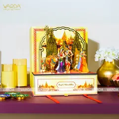 This custom invitation box features a stunning 3D pop-up scene of a divine couple, set against a temple backdrop. The drawer below can hold sweets or other keepsakes, making it a truly interactive and memorable invitation.
