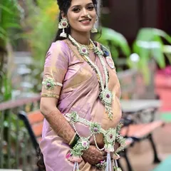 A beautiful portrait of a mom-to-be, showcasing her pregnancy glow. The makeup is kept soft and luminous to complement her lilac silk saree and the intricate floral jewelry for her Dohale Jevan.