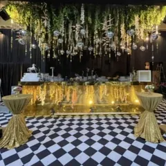 We love creating unique, themed spaces like this retro-glam bar. The setup features a gold-mirrored bar, a classic checkered dance floor, and a ceiling installation of hanging greenery and disco balls for a memorable party zone.