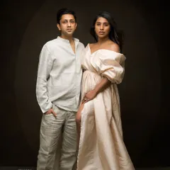 A high-fashion, fine art portrait of a couple. The dramatic lighting and their strong poses create a striking image reminiscent of a magazine editorial.