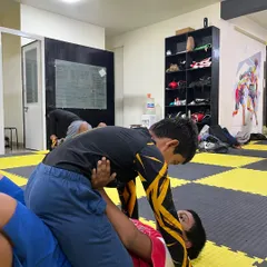 A student practices maintaining side control during a grappling session. This fundamental position is key to controlling a match in jiu-jitsu.