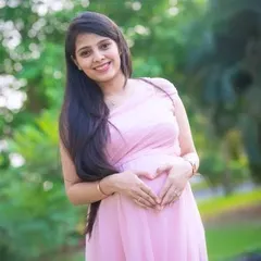 A classic maternity portrait of an expecting mother making a heart shape with her hands on her belly. This pose beautifully highlights the baby bump.
