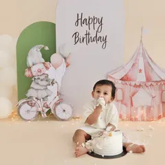 A taste of birthday fun. This shot captures the moment just before the real mess begins, with the birthday boy curiously tasting his cake. The simple, elegant setup with a circus tent background adds a touch of magic.