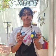 A young artist proudly displays the clay birds she made and painted during our kids' workshop. We encourage children to explore form and color.