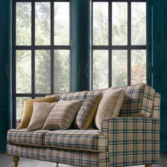 A classic sofa upholstered in a timeless plaid fabric. The shot is framed by large windows, creating a bright and airy feel that showcases the fabric in natural light.