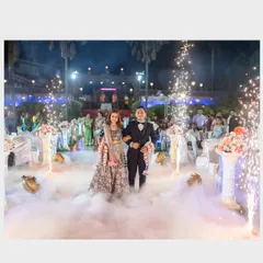 A wide shot of the couple's grand entrance at their outdoor reception, complete with fog and pyrotechnics for a stunning visual effect.