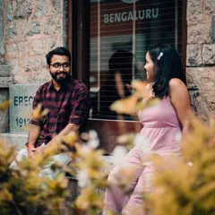 A candid conversation between a couple sitting outside a building with a "Bengaluru" sign. We love incorporating elements of the city to ground your story in a sense of place.