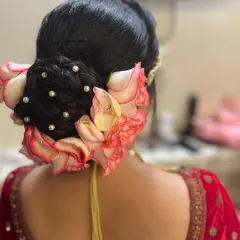 A classic bridal bun adorned with beautiful pink and white roses and small pearls for a touch of elegance.