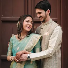 A close-up candid moment showing the couple's easy laughter and connection, with their elegant traditional outfits complementing the classic setting.