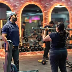 Coach Arun provides direct supervision as a client performs an overhead press. This one-on-one attention is what helps you get results faster and safer.