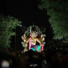 A wide shot of the Sanpadya Cha Maharaja Aagman Sohala, showing the scale of the idol as it moves through the streets at night, surrounded by devotees.