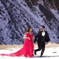 A beautiful shot from a pre-wedding shoot in the snow. The vibrant red of the trail gown stands out beautifully against the white landscape, creating a truly memorable photo.