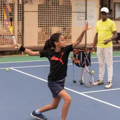 A young player executes a forehand with perfect form while her coach observes. We provide close, technical supervision to ensure our junior athletes develop the right habits from the very beginning.